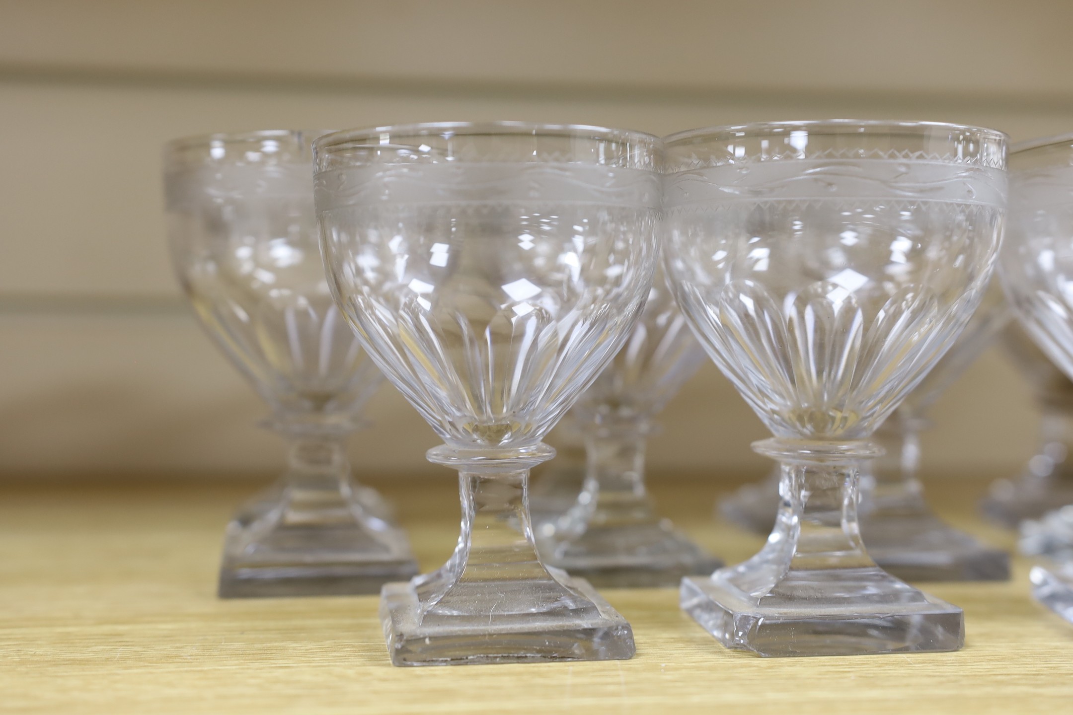 A set of eleven early 19th century engraved wine glasses, square foot, 11cm tall